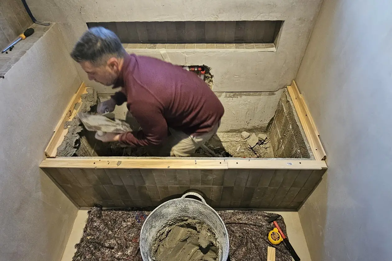 César aplicando mortero a mano en un baño